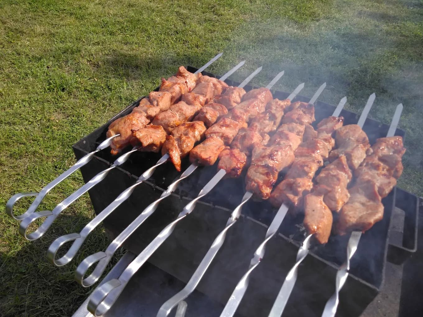 Schaschlik-Spieße auf dem Grill im Garten, leicht rauchend